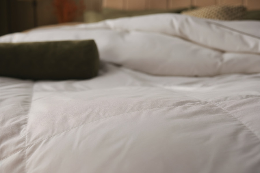 Close-up of a folded Sleepeezee duvet corner beside a green bolster pillow